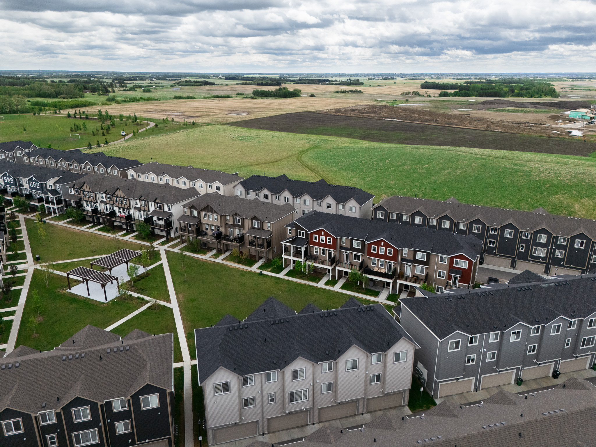Aerial view of an Edmonton townhome community bordering open farmland